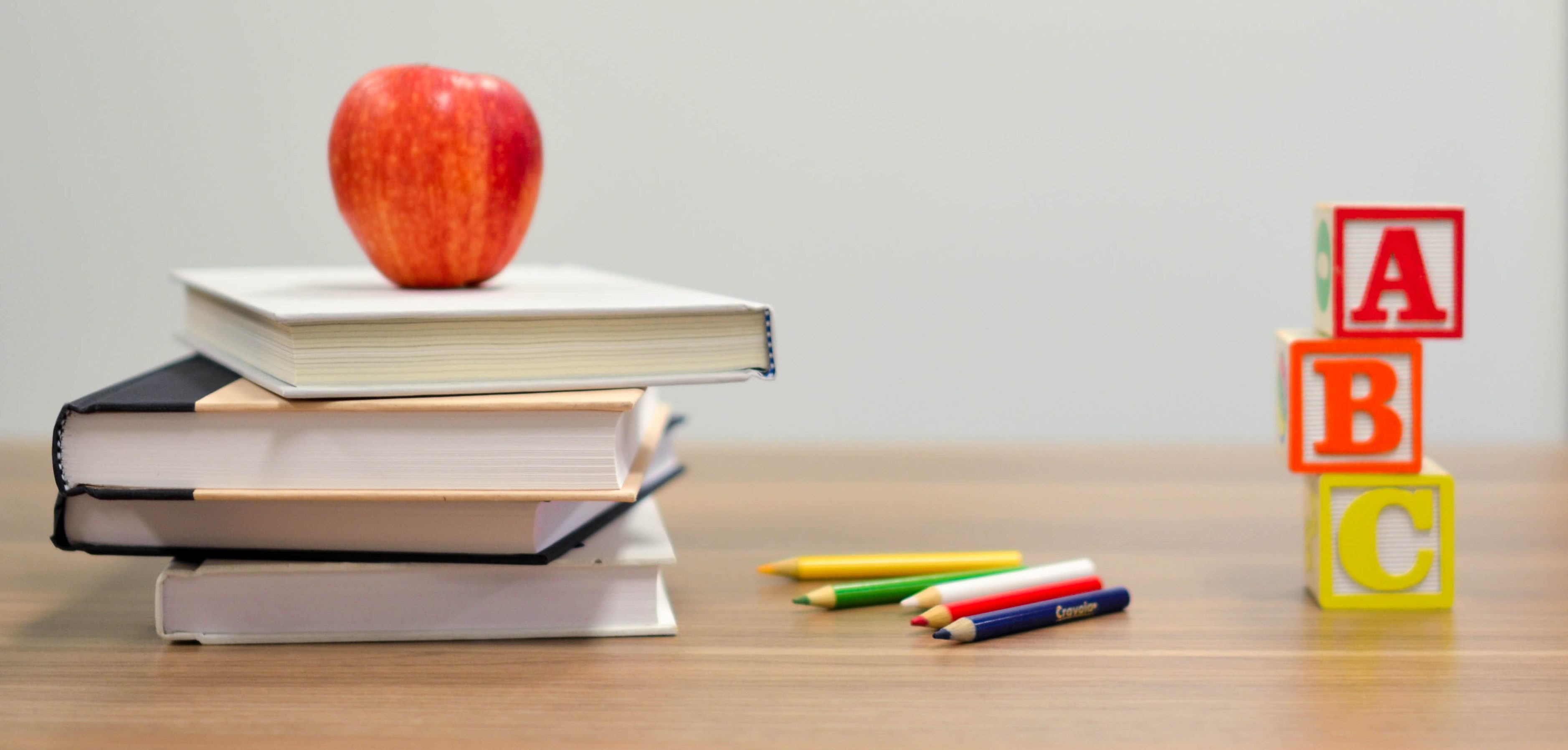 A suggested stack of books and an apple one might have when they earn money teaching English at home with SayABC.com.
