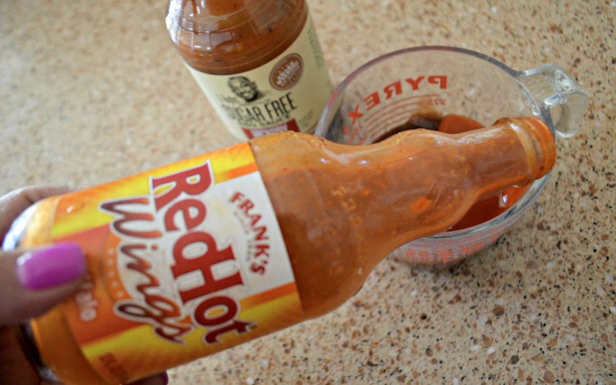 pouring frank's wing sauce into measuring cup