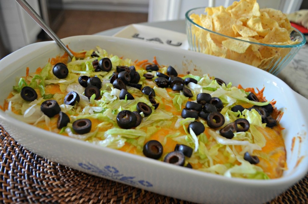 baked taco dip topped with lettuce and olives
