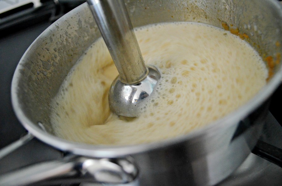 using an immersion blender to mix pot contents