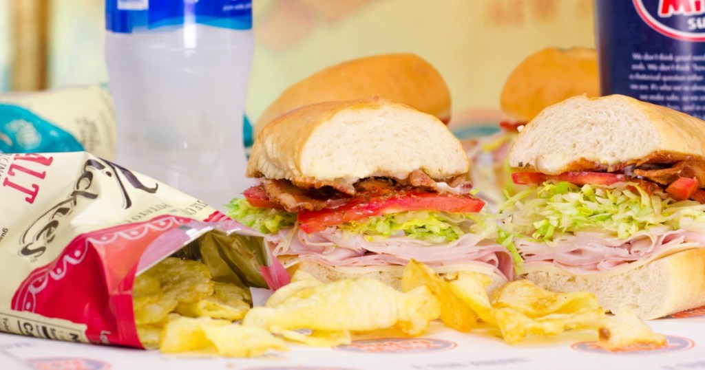 Jersey Mike's Sub on table with bag of chips and beverage