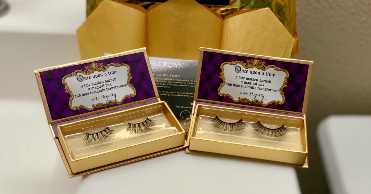 two sets of black false lashes sitting in gold and purple boxes on white countertop