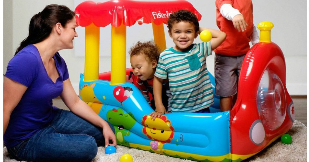 mom playing with kids in an inflatable ball pit