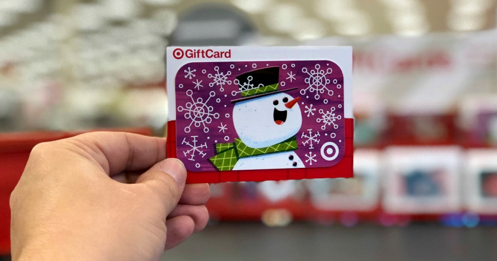 person holding Target gift card featuring a snowman