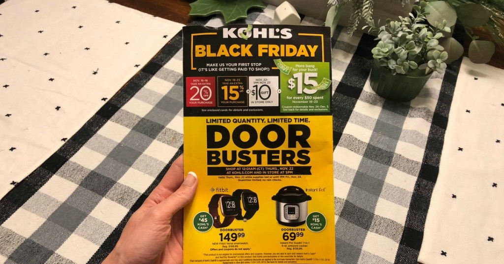 hand holding kohls black friday doorbuster flyer over decorated table