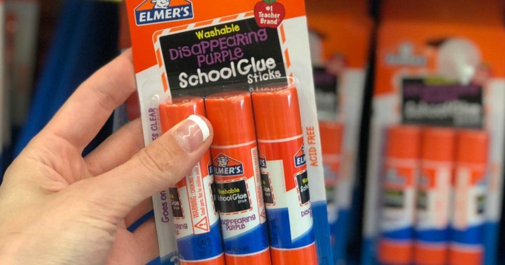 woman's hand holding elmer's glue stick in -store