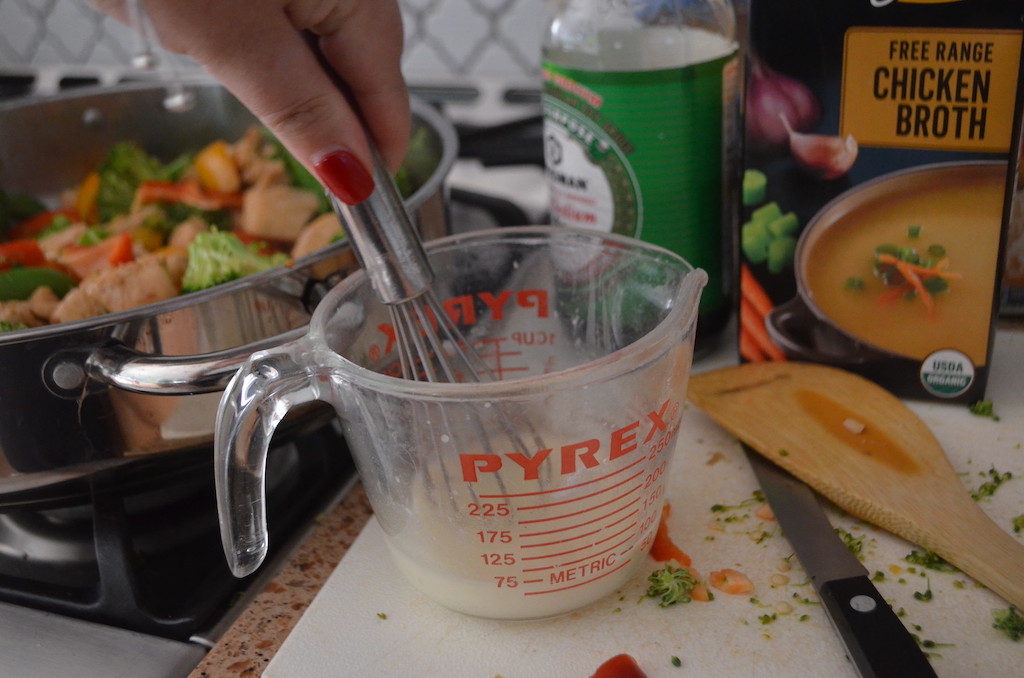 pan with chicken stir fry and mixing sauce in pyrex glass measuring cup 