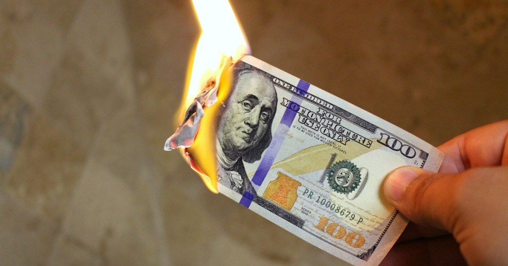 $100 bill burning on fire ways to stop wasting money