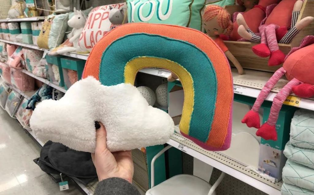 hand holding a rainbow and cloud pillow