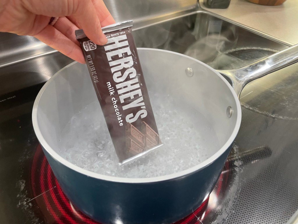 Woman using clever cooking hacks to melt a Hershey Bar using a saucepan