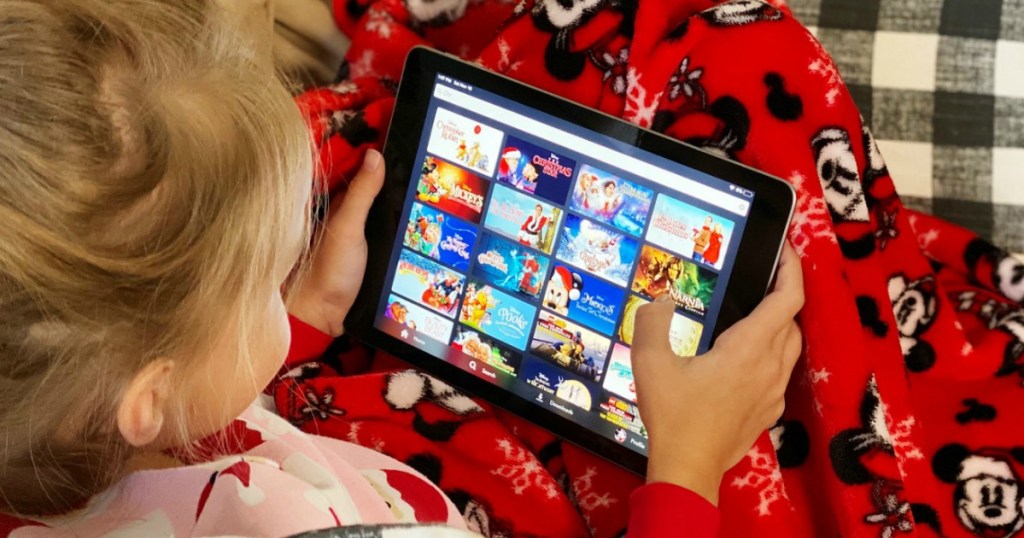 little girl on iPad using the Disney+ app with movies