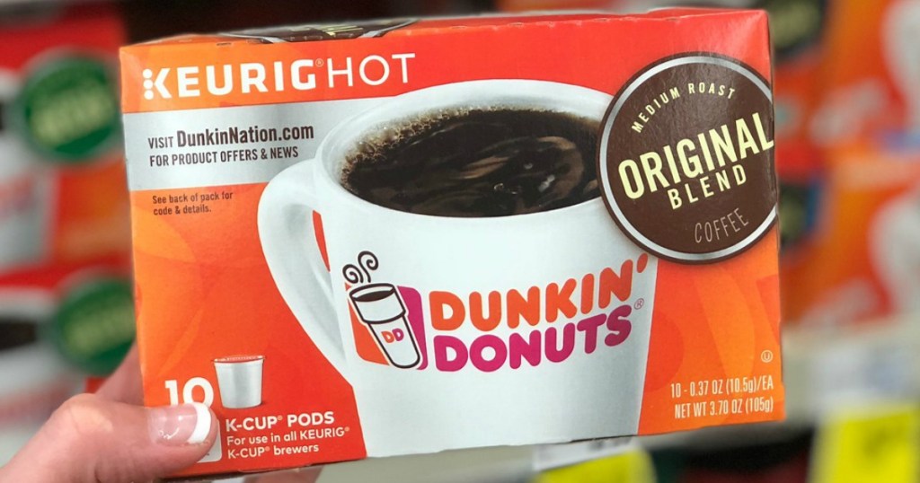 hand holding keurig hot dunkin donuts in store with blurry background