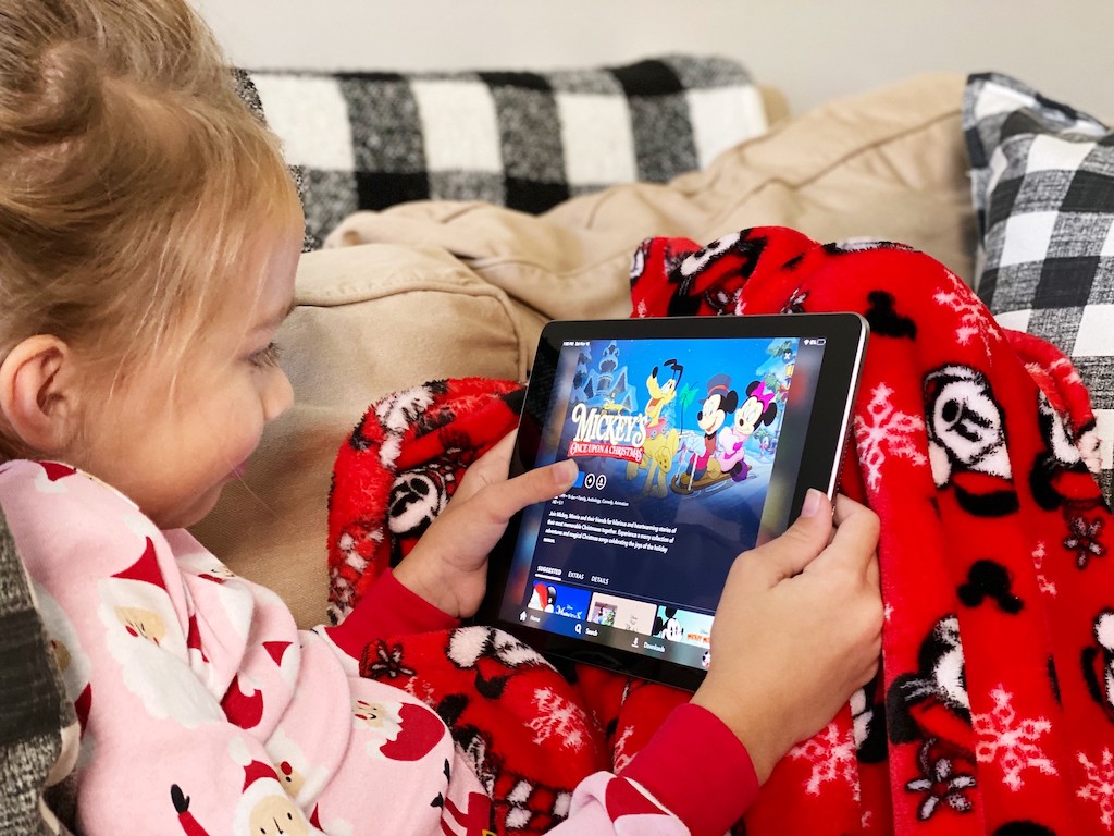 little girl watching disney movie on iPad with Mickey Mouse blanket