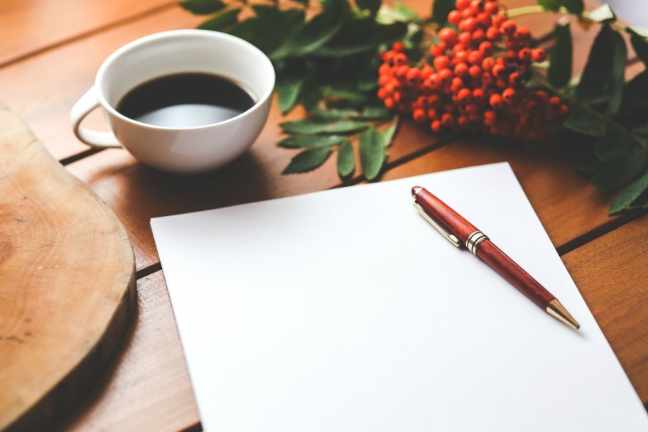 blank piece of paper and pen next to a cup of coffee