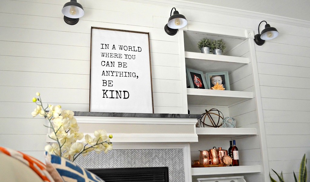 be kind sign above mantle in living room