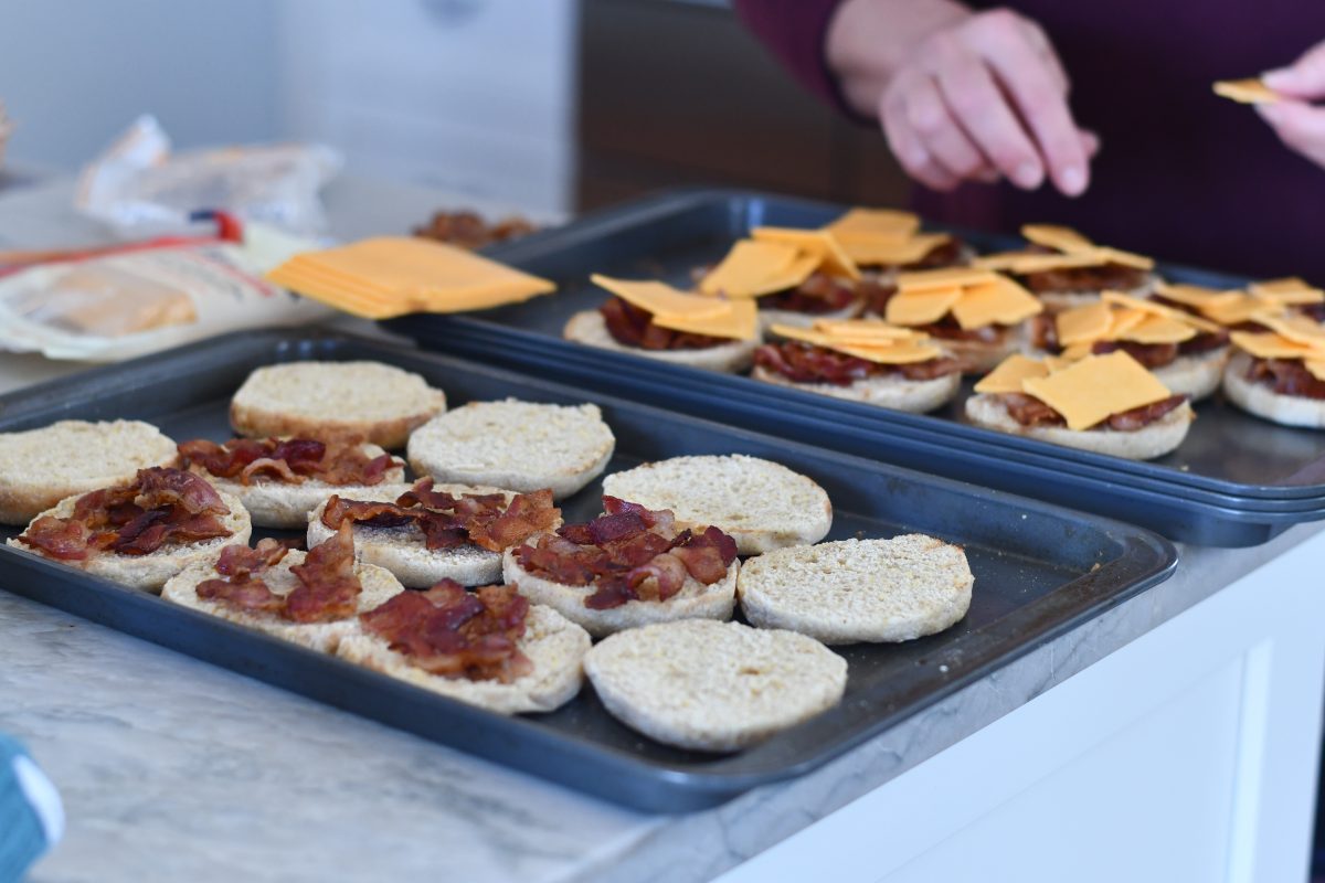 melted bacon and tomato english muffins on a baking sheet 