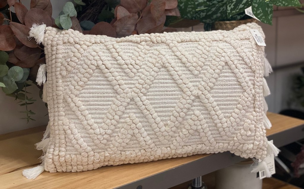 close up of textured cream lumbar throw pillow on wood shelf