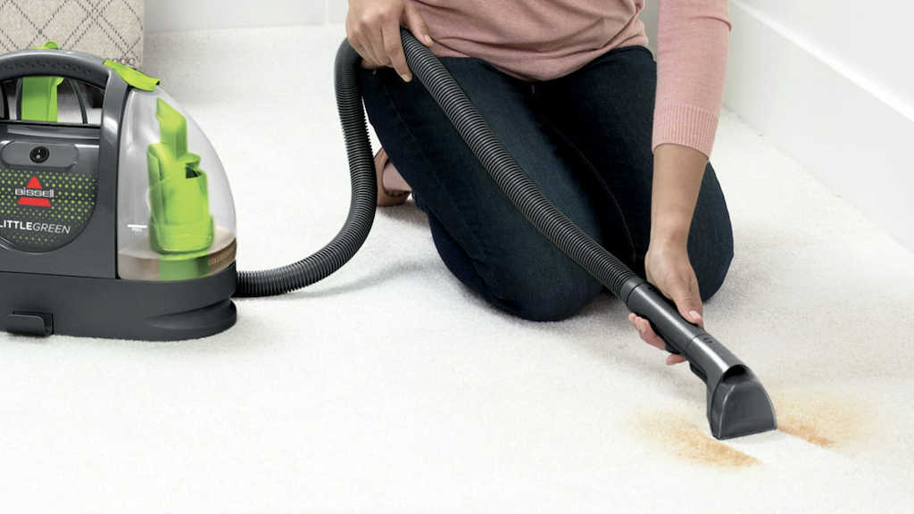 woman on her knees using the Bissell little green carpet cleaner