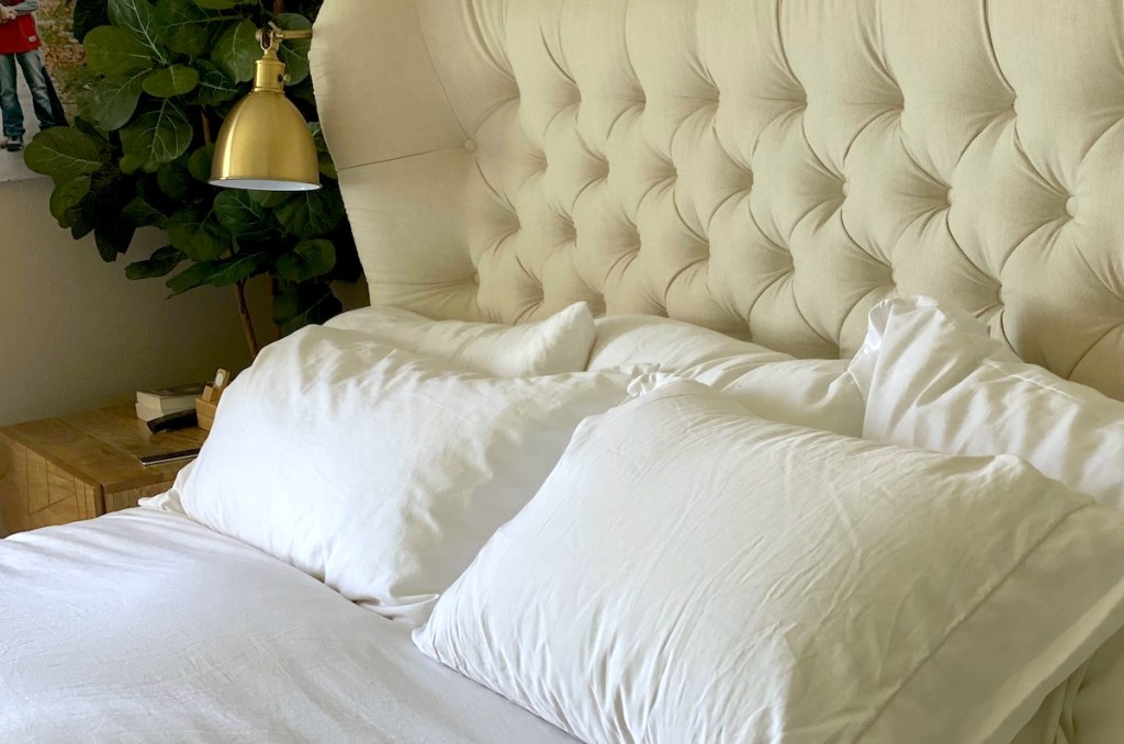 tufted bed headboard with white pillows and sheets on bed