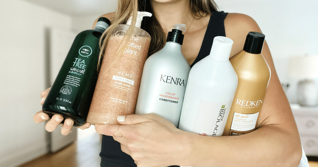 woman holding liter sized shampoo and conditioner bottles