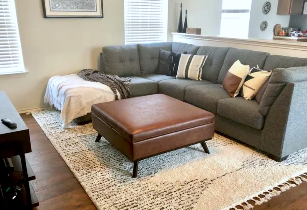 brown leather ottoman in living room with gray couch