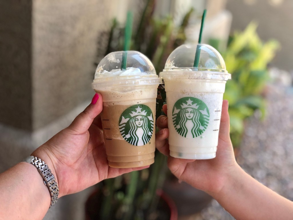 hands holding two starbucks drinks
