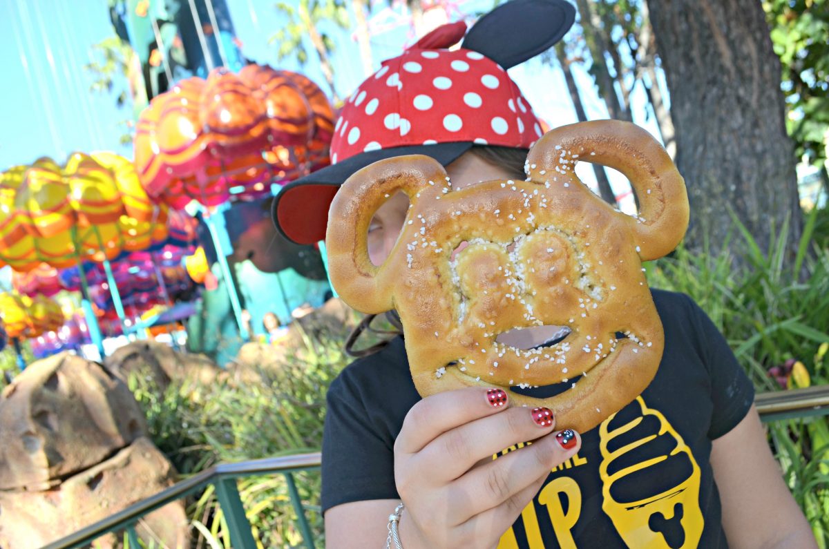 young girl holding a Mickey Mouse salted soft pretzel