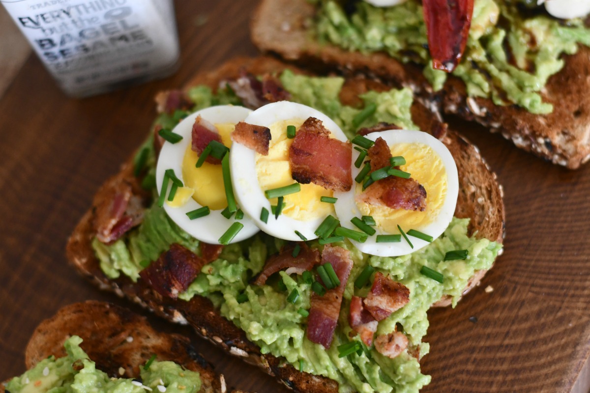 bacon and egg avocado toast with fresh chive garnish 