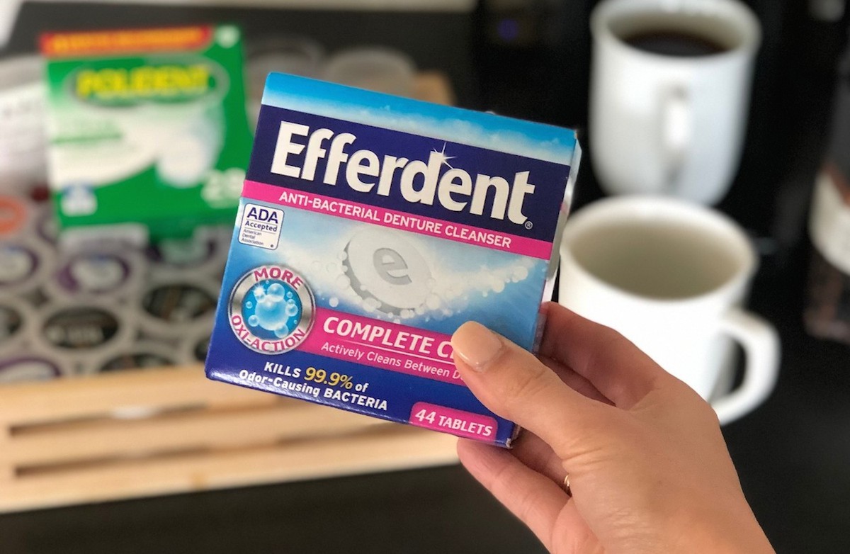 hand holding a box of efferdent tablets with k-cups in the background