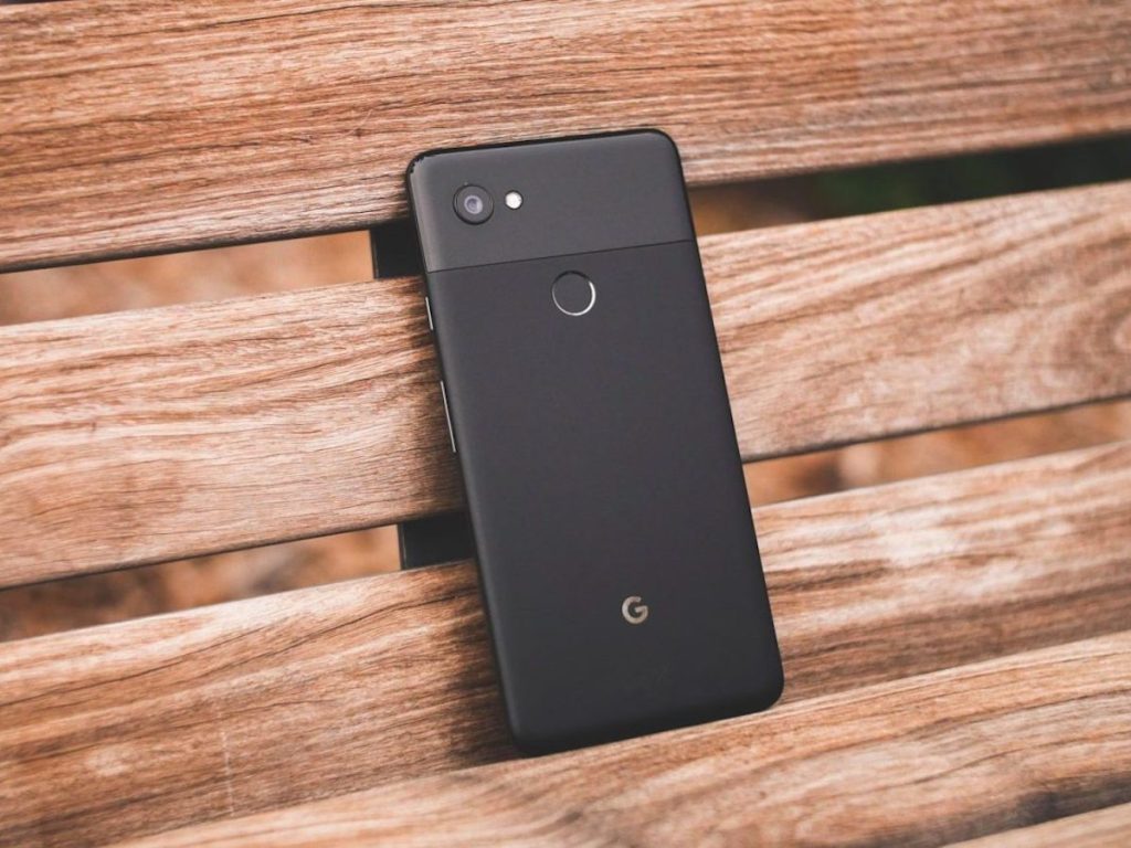 hand holding black google pixel on wooden bench