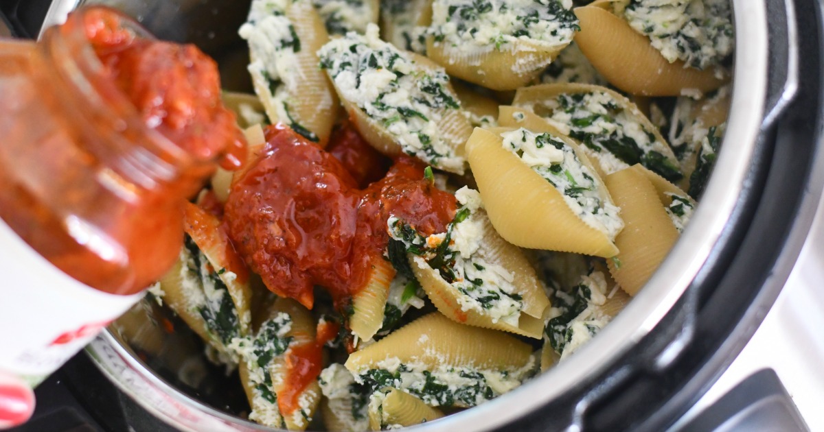 pouring marinara sauce over stuffed shells using the instant pot