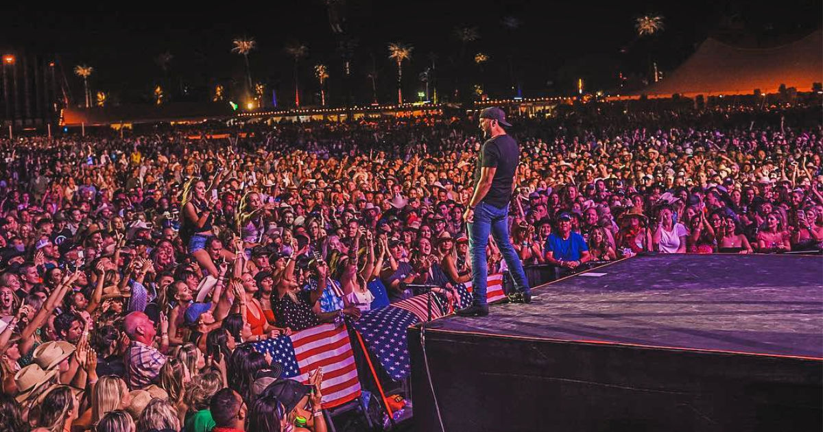 musical artist performing on stage at a concert to a large audience
