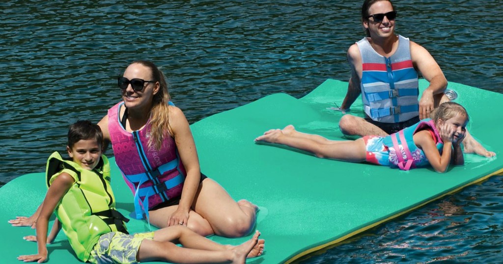adults and kids sitting on green float in water
