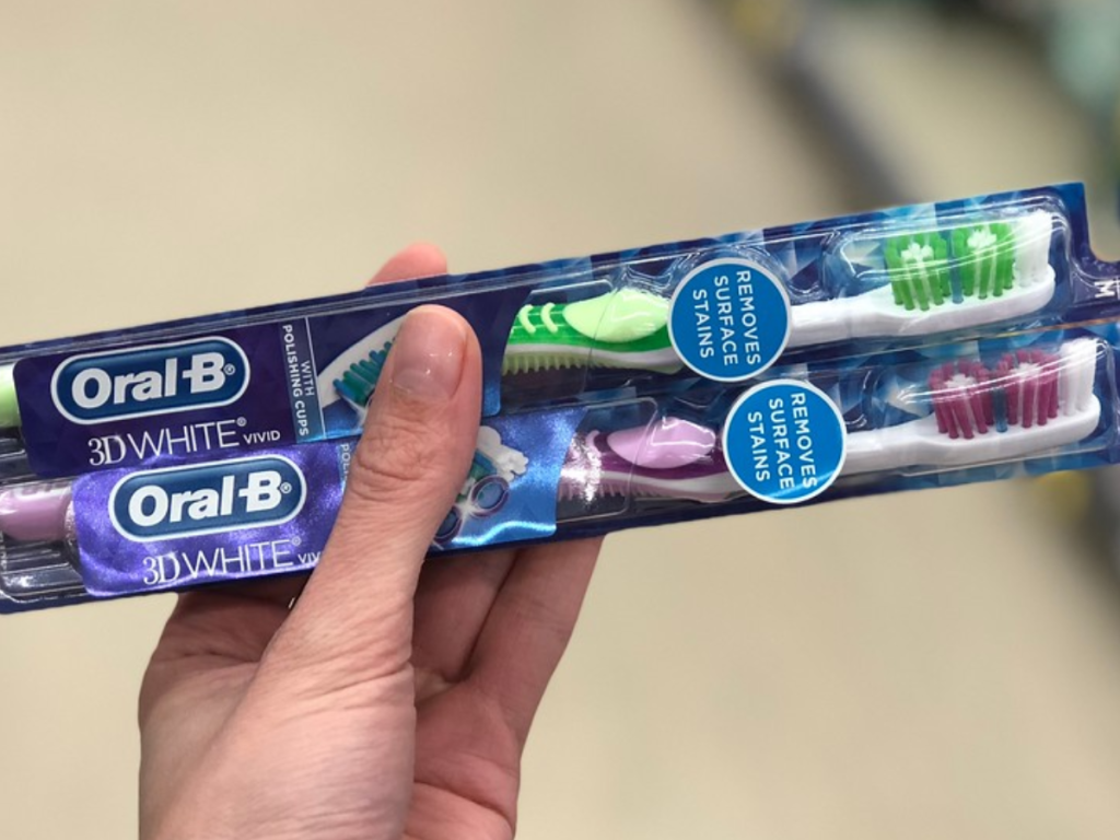 Woman's hand holding Oral-B toothbrushes with blurred background