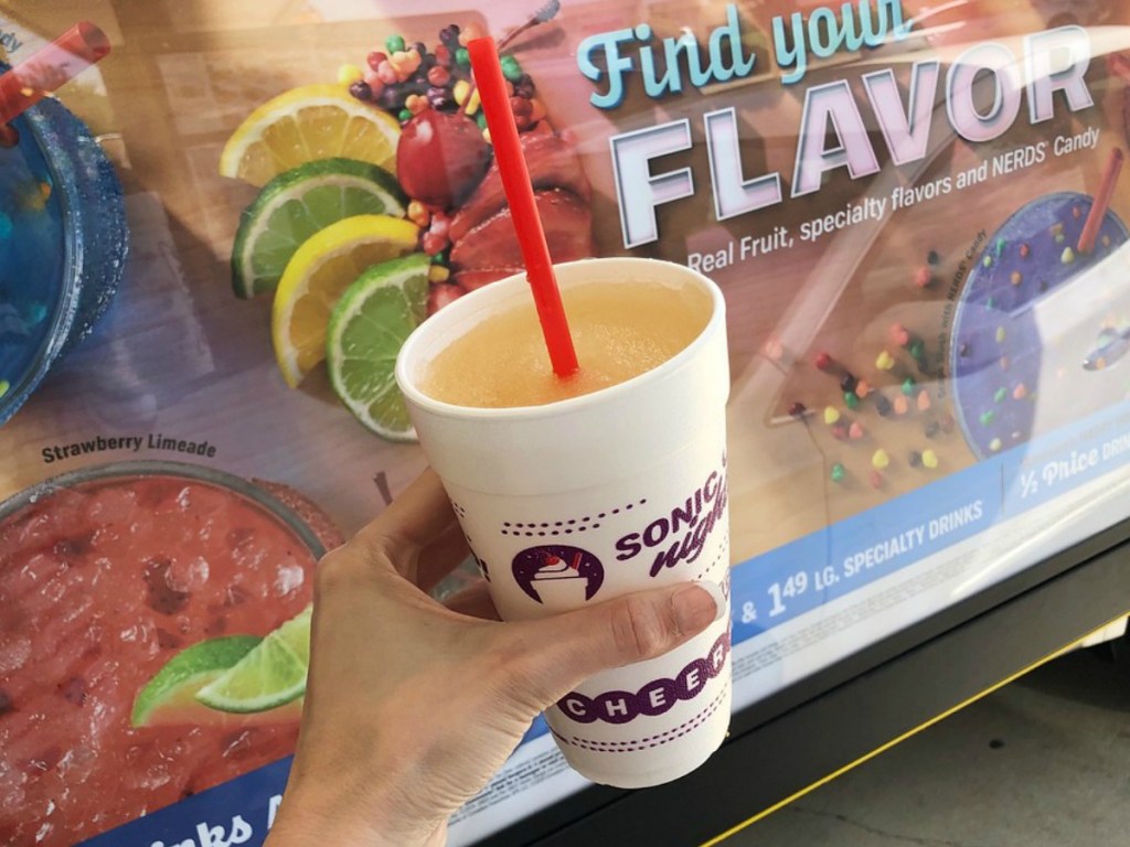 hand holding Sonic drink in front of Sonic menu sign