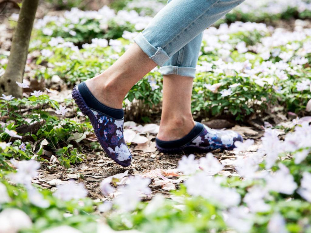 woman walking through grass with clogs on