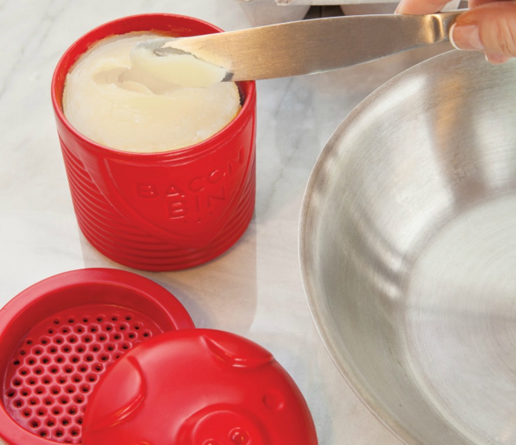 hand holding a red pig shaped bacon bin with strainer