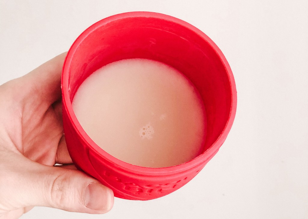hand holding a red bin with white grease inside
