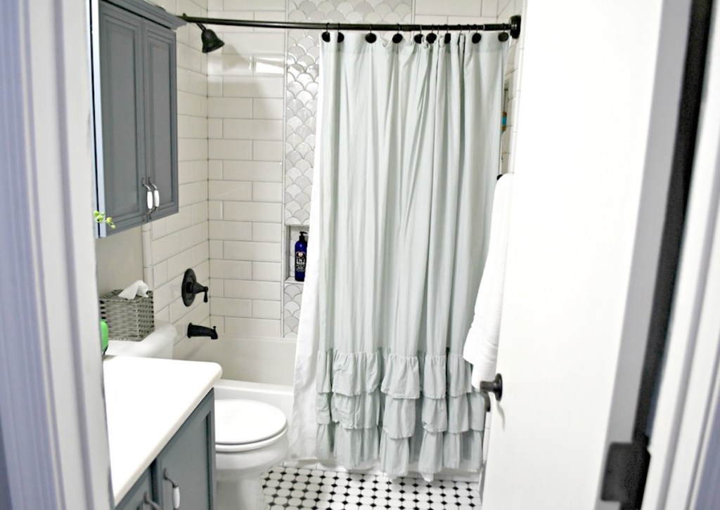 bathroom with ruffle shower curtain and white tile