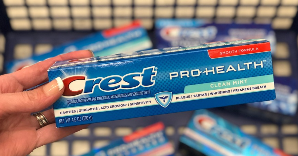 hand holding box of Crest pro-health toothpaste over shopping basket