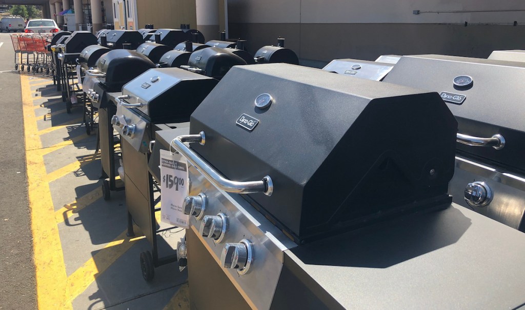 various types of outdoor grills lined up outside on pavement in front of home depot store