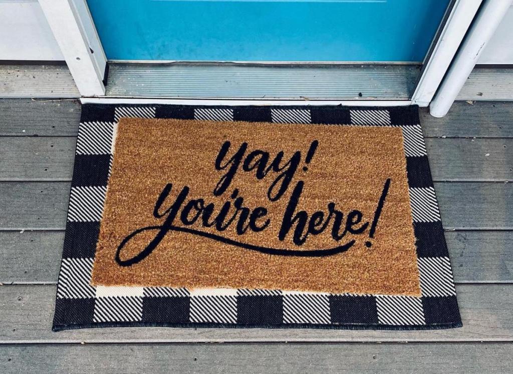 yay you're here and white and black check doormat at blue front door
