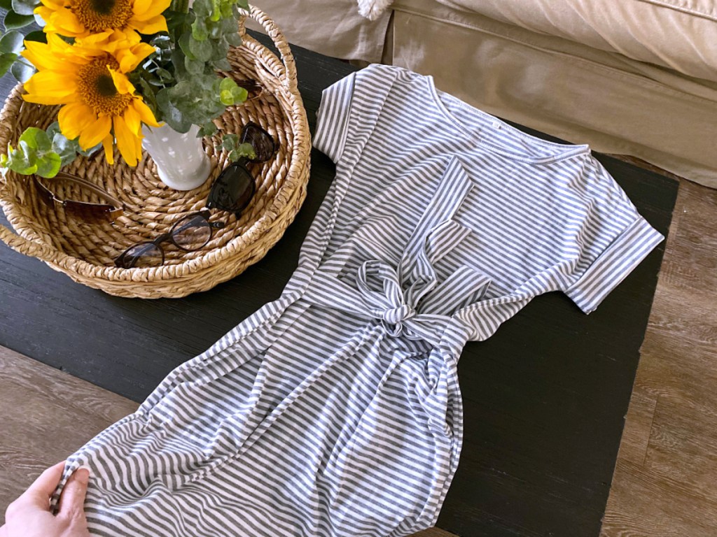 short sleeve stripe dress laying on table with basket full of sunflowers and sunglasses