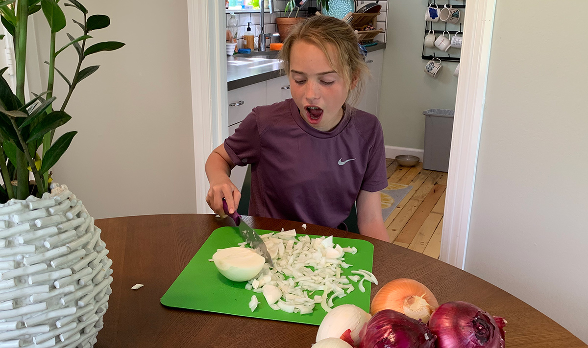 collin's daughter cutting white onion with mouth open to prevent tears