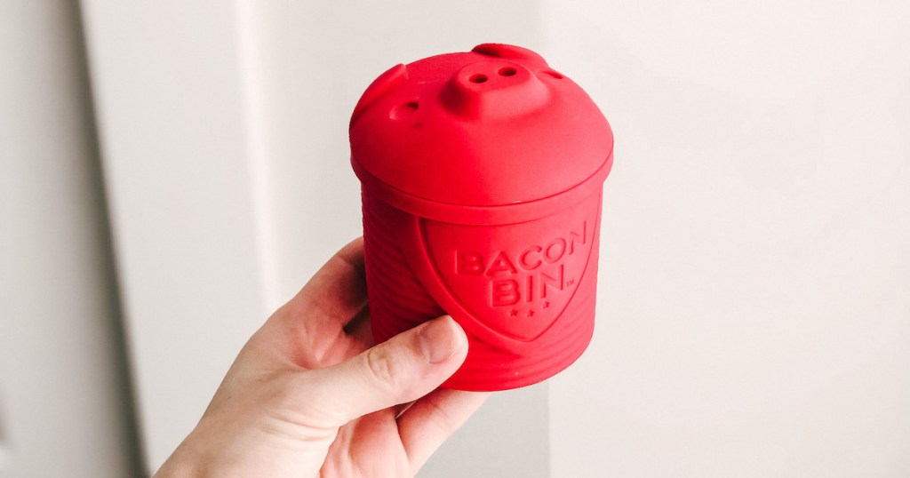 hand holding a red pig shaped bacon bin