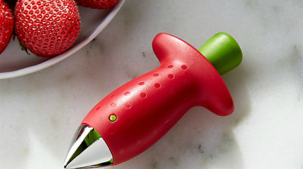 hand holding a red strawberry huller 