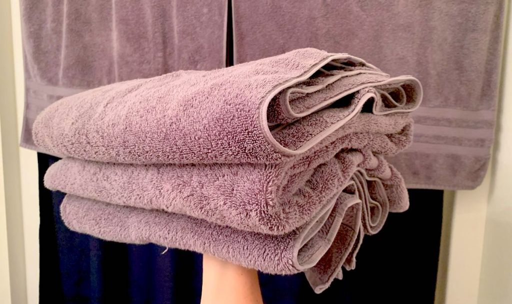 arm holding up pile of purple towels 
