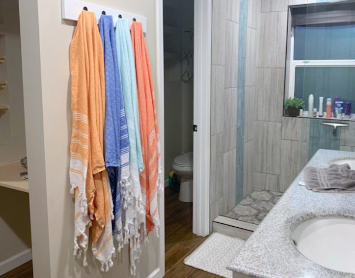 row of bright colorful bath towels hanging on wall in bathroom