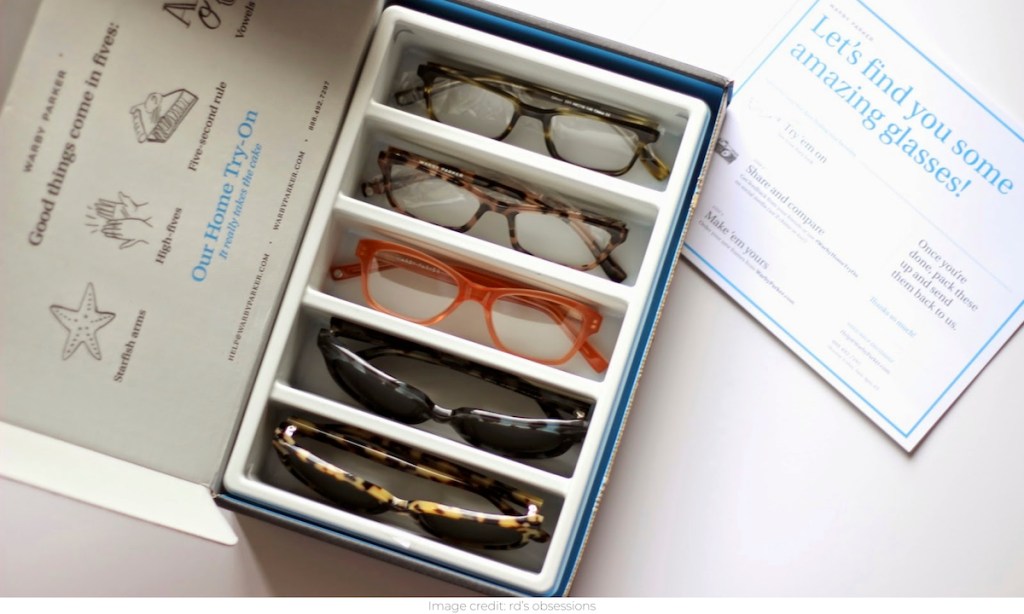 box of five pairs of sunglasses and glasses sitting on white counter