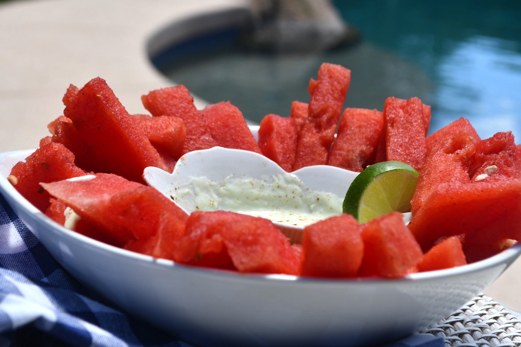 chile lime watermelon fries in bowl with pool in the background